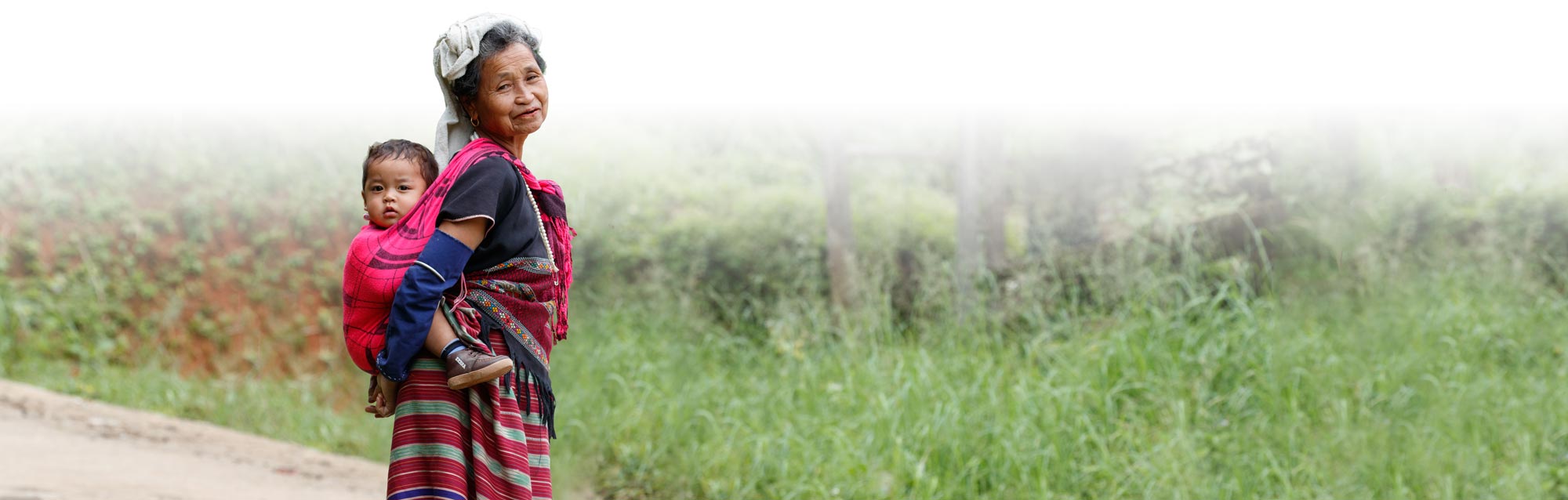 Southeast Asian woman carries a small child on her back