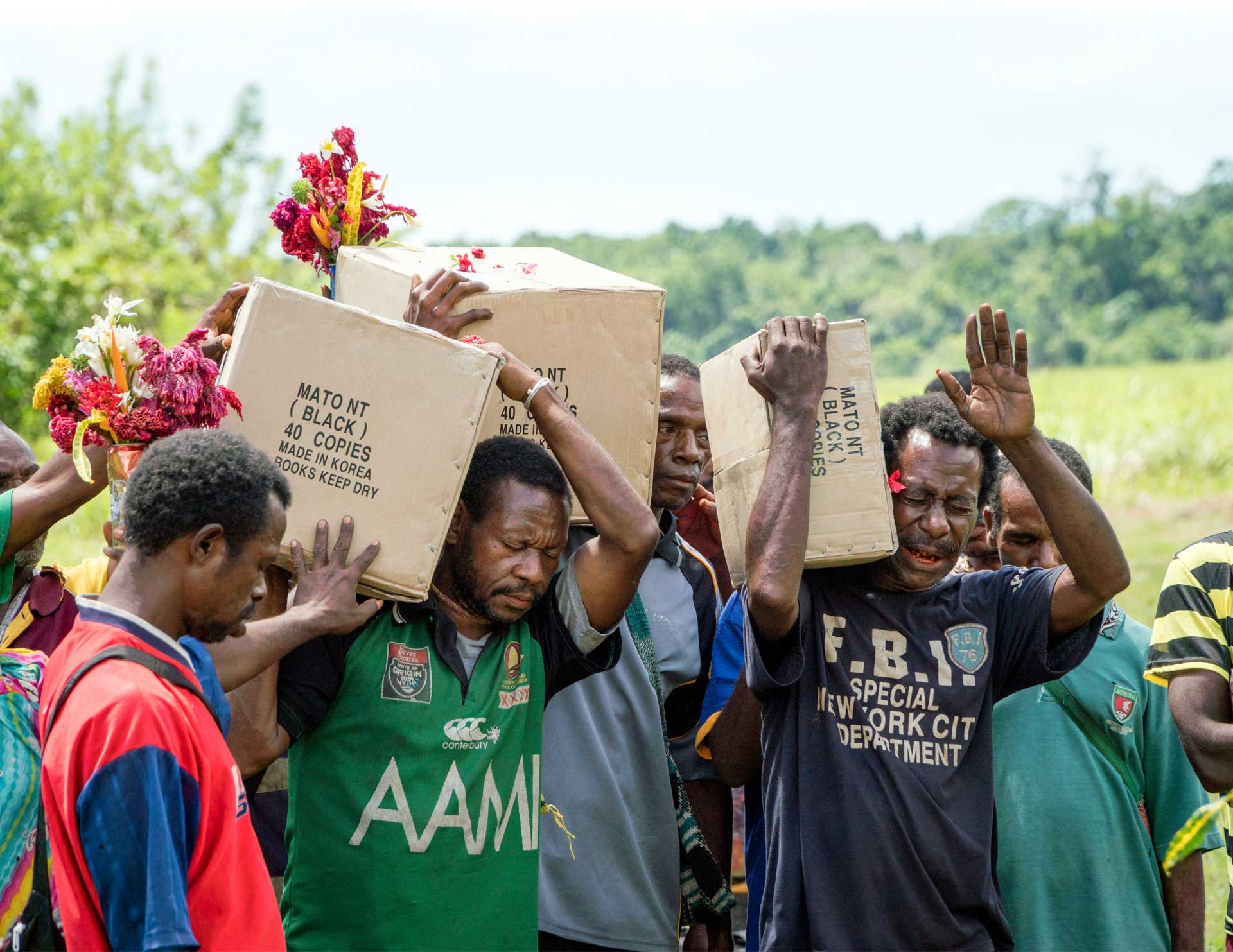 Pacific men carrying boxes of New Testaments