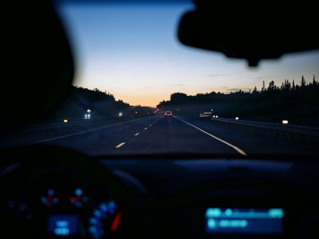 Person driving in the car at dawn.