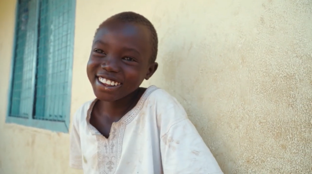 Child smiling next to building