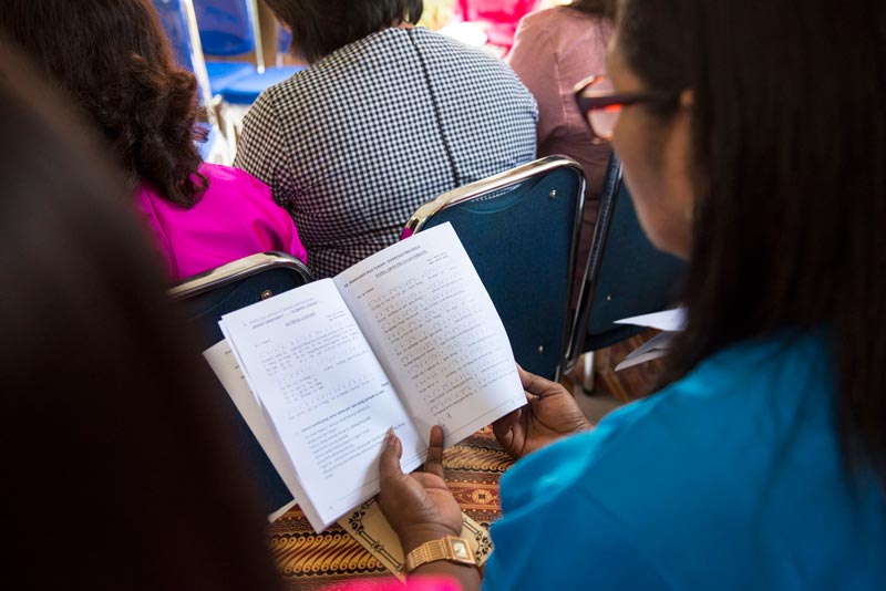 Person holding an open church liturgy booklet.