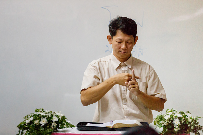 Pastor Montri preaching by signing.