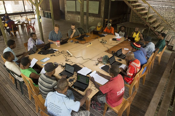 A group of men working around a table together, discussing the translation for their individual language communities A group of men working around a table together, discussing the translation for their individual language communities