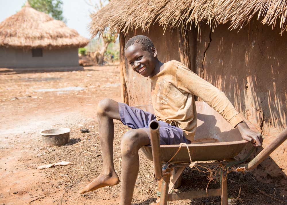 Smiling boy sitting in a wheelbarrow.