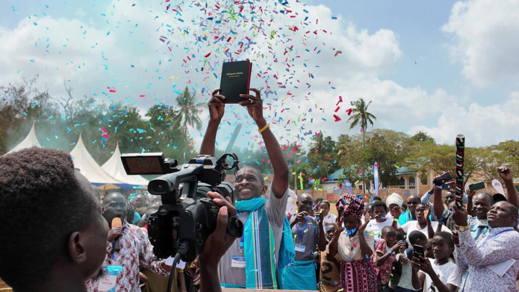 Man holding up Scripture at the Chonyi New Testament Scripture Celebration in Kenya.