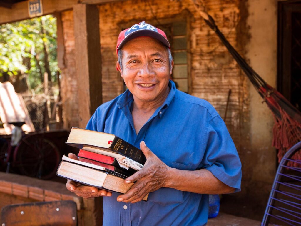 Latino man holding a stack of Bibles.
