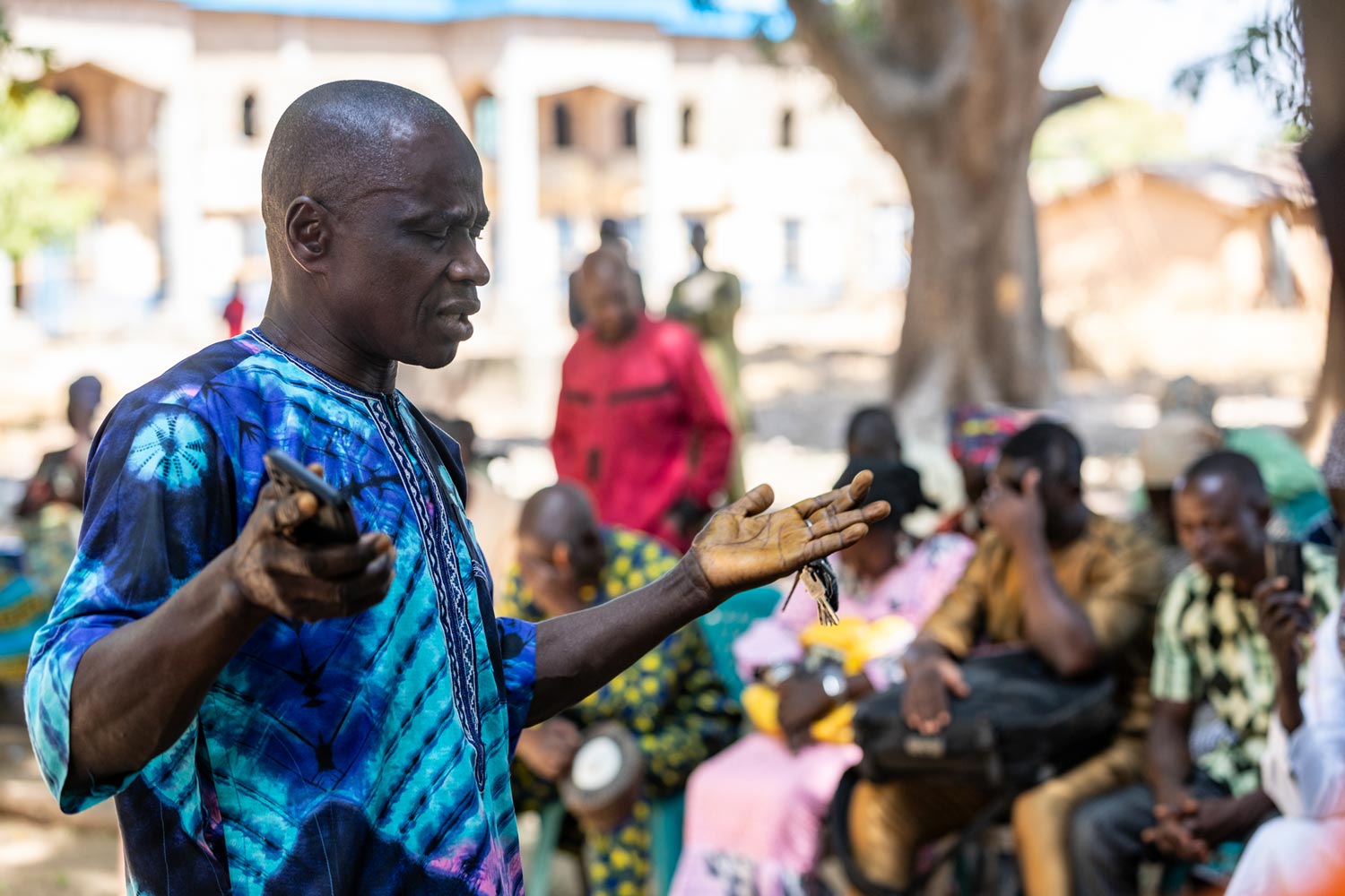 /></figure>
<p class= Africa Nigeria man praying with arms raised and others around him praying