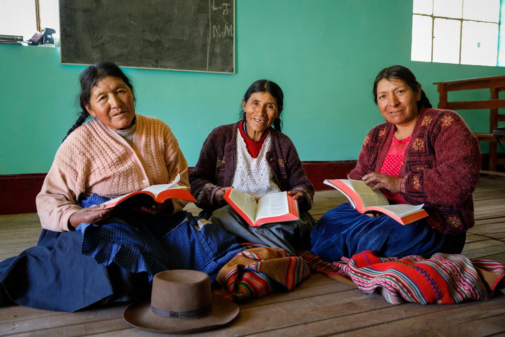 Three women seated at church holding Bibles in Peru