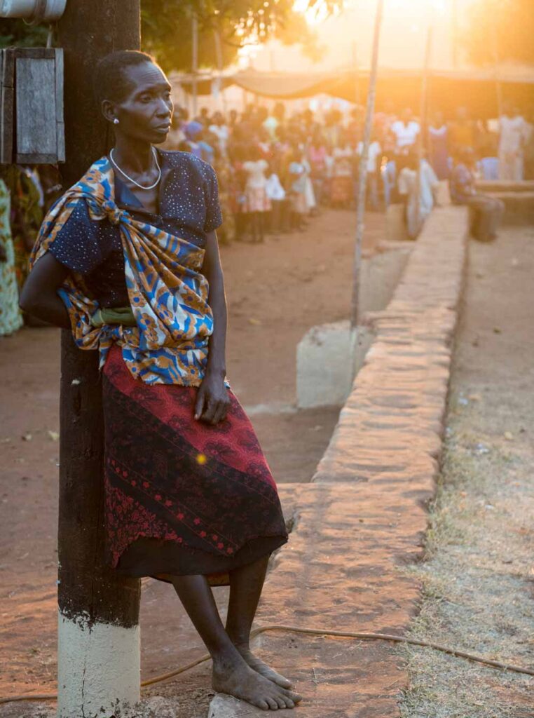 Woman leaning against a pole.