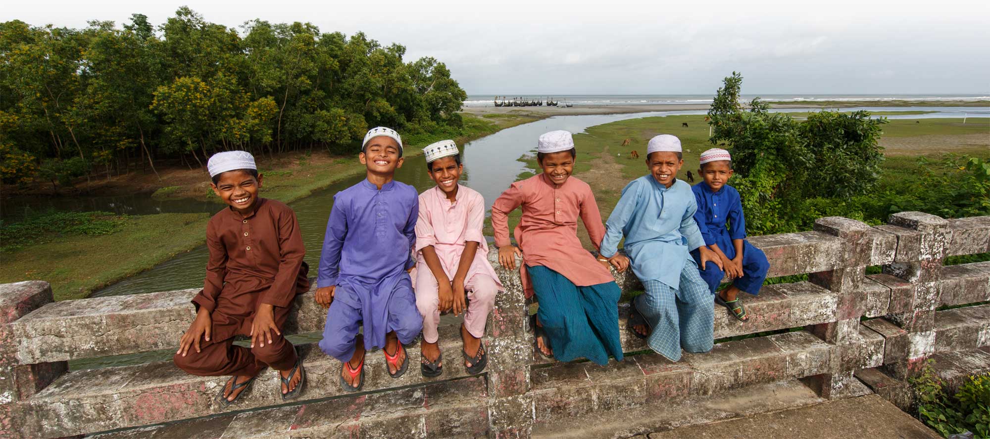 Row of boys sitting on a bridge