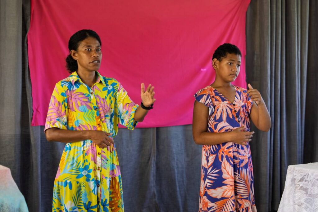 A woman and a girl lead worship in a sign language in Fiji.