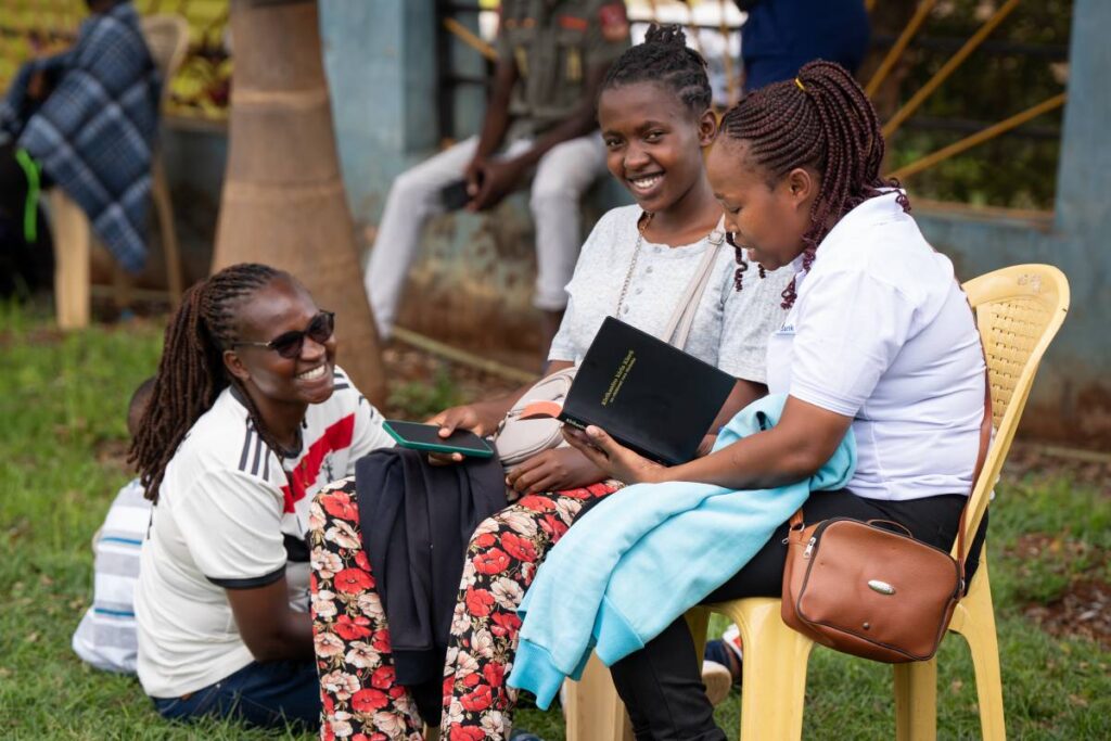 Three girls talking and holding Chuka New Testaments.