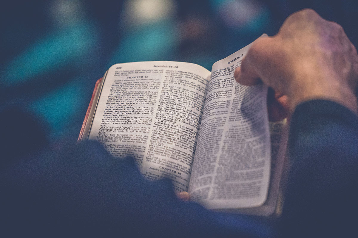 Open Bible with someone turning the page.