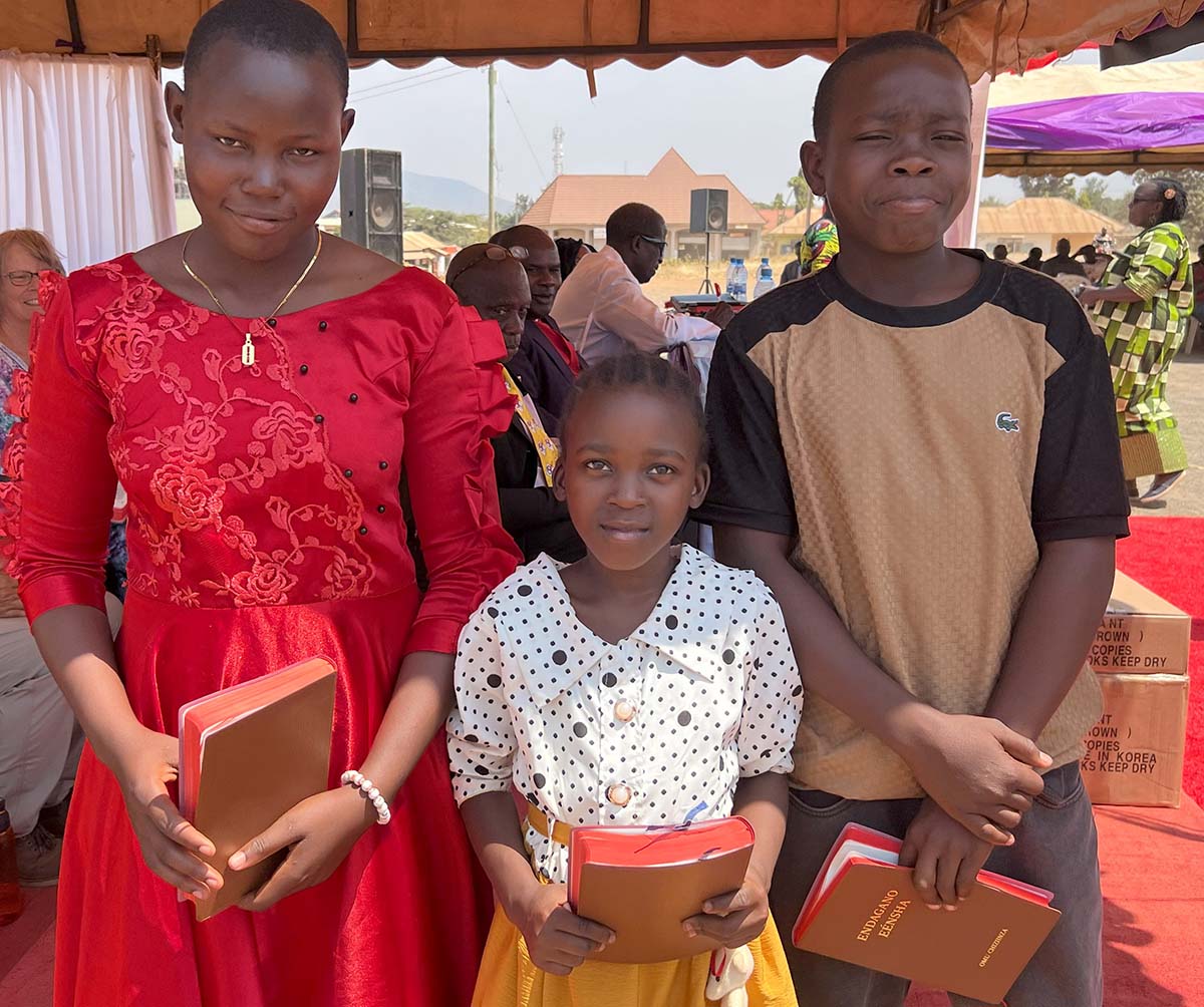 Three Zinza children holding New Testaments