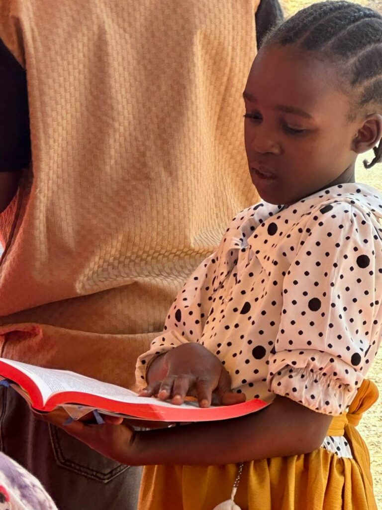 Zinza girl holding New Testament.