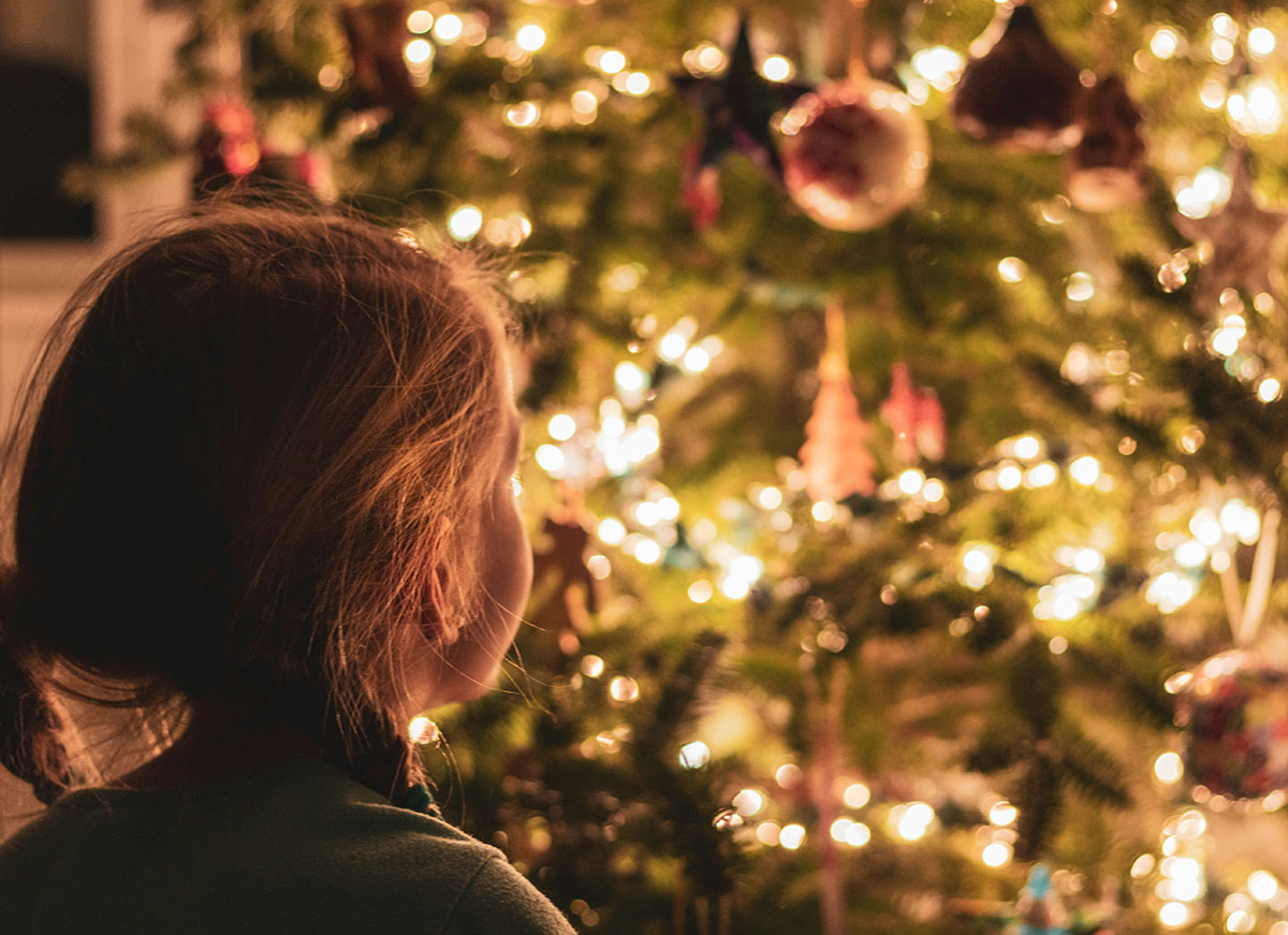 Child looking in wonder at a brightly lit Christmas tree
